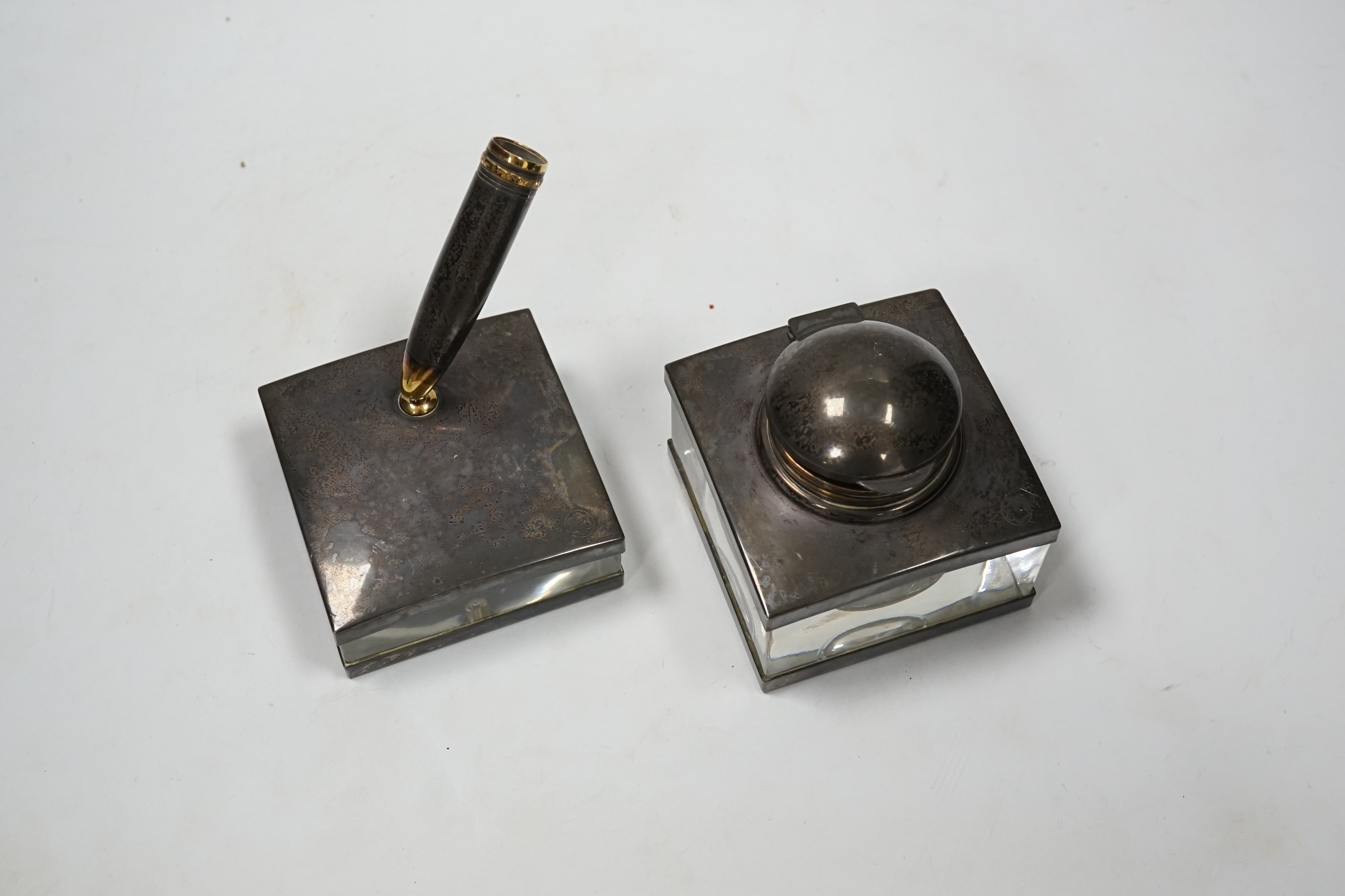 A Montblanc three piece German silver and glass desk set comprising pen stand, inkwell and blotter, each glass mounted, silver engraved with the Montblanc logo